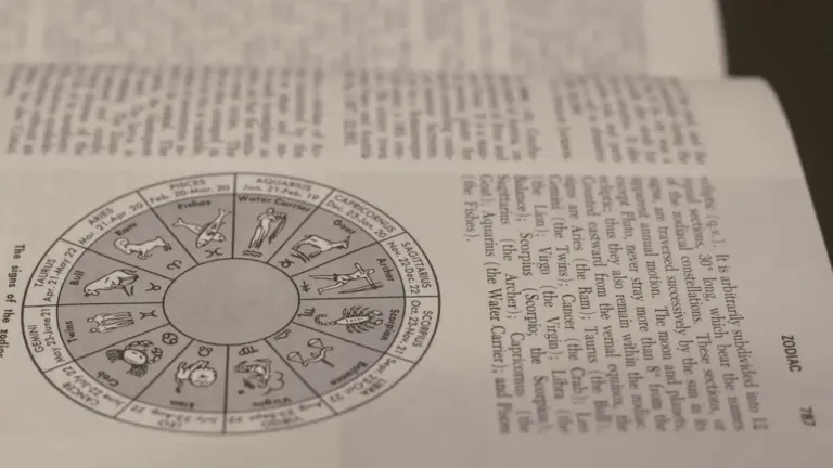 Księga z ilustracjami znaków zodiaku otwarta na stronie z astrologicznymi opisami.
