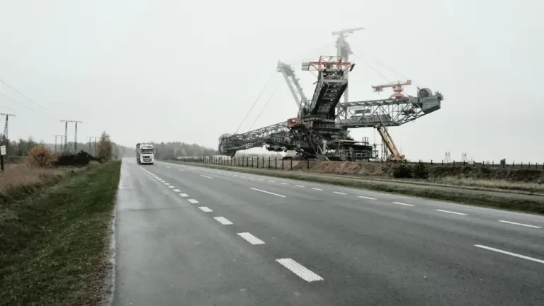 Gigantyczna koparka przemysłowa transportowana wzdłuż drogi w krajobrazie industrialnym Polski
