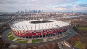 Widok z lotu ptaka na Stadion Narodowy w Warszawie na tle panoramy miasta.