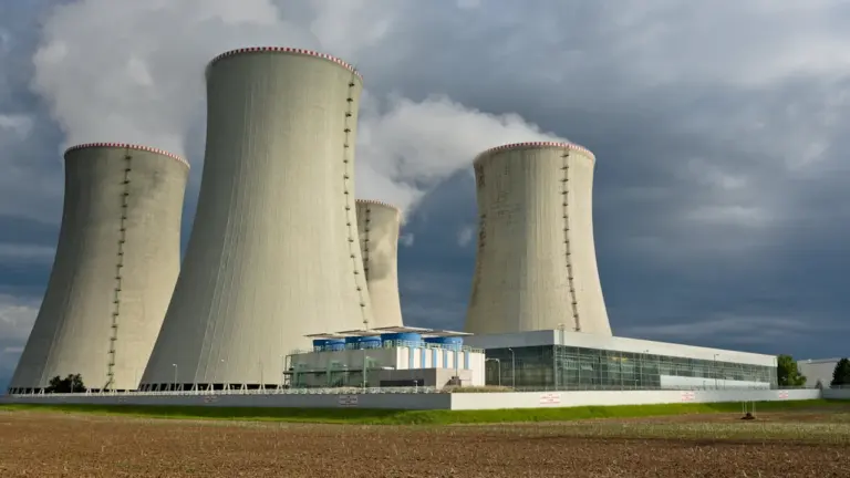Chłodnie kominowe elektrowni węglowej w Polsce pod zachmurzonym niebem w ciągu dnia.