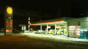 Oświetlona stacja paliw w nocy przykryta śniegiem, symbolizująca nadchodzące zmiany cen paliw w Polsce.