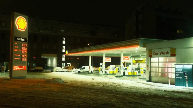 Oświetlona stacja paliw w nocy przykryta śniegiem, symbolizująca nadchodzące zmiany cen paliw w Polsce.