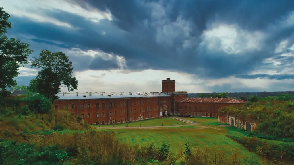 Historyczny budynek Twierdzy Modlin pod dramatycznym, zachmurzonym niebem w jesienny dzień.